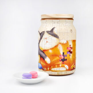 A Take a Nap Puzzle Jar Large with a cat on it next to a bowl of candy, creating a whimsical puzzle.